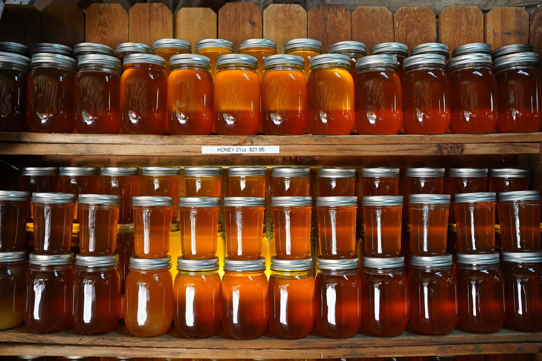 a beekeeper arranging labeled honey jars at a farmers market stall